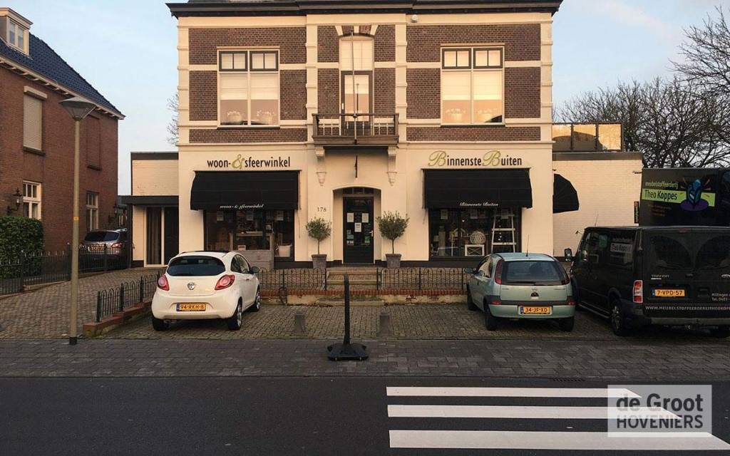 Voorgevel van een gebouw met geparkeerde auto's