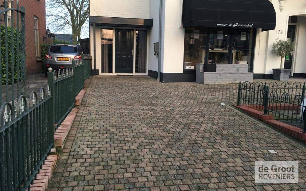 Bestrate entree voor een gebouw met zwarte zonwering
