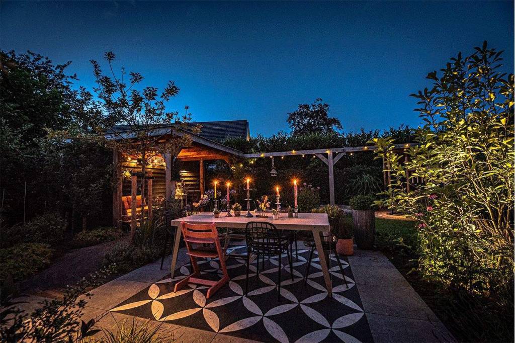 Verlicht terras met eettafel en houten overkapping