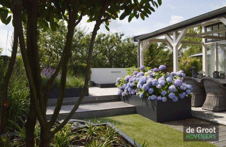 Verhoogd terras met witte overkapping en bloembakken