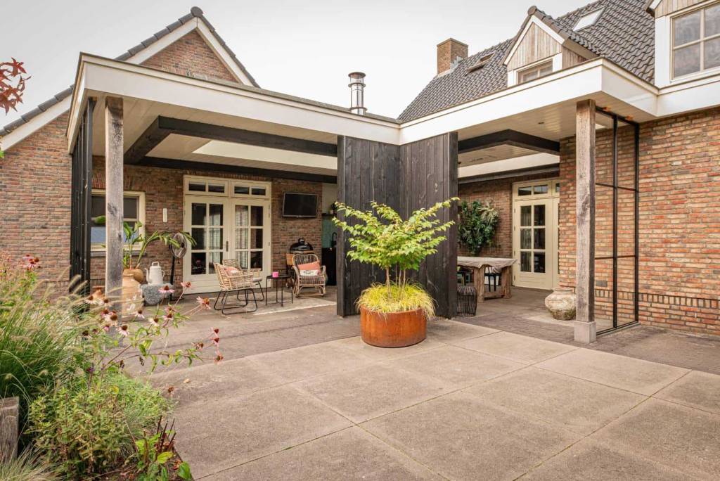 Overdekt terras met houten staanders bij bakstenen woning
