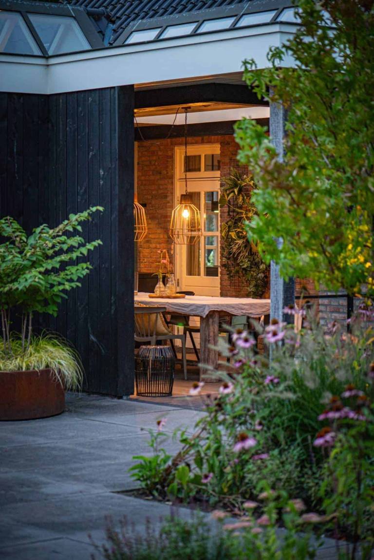 Tuinpad langs bloemborders naar een overdekt terras