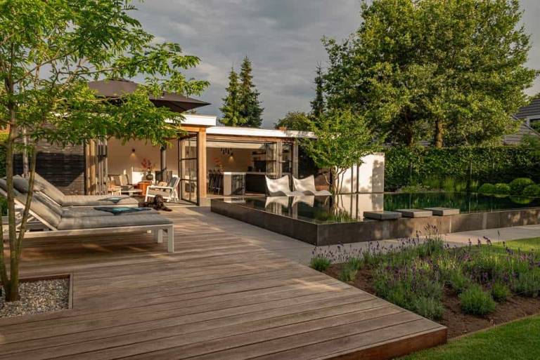 Houten vlonder met ligstoelen bij een poolhouse