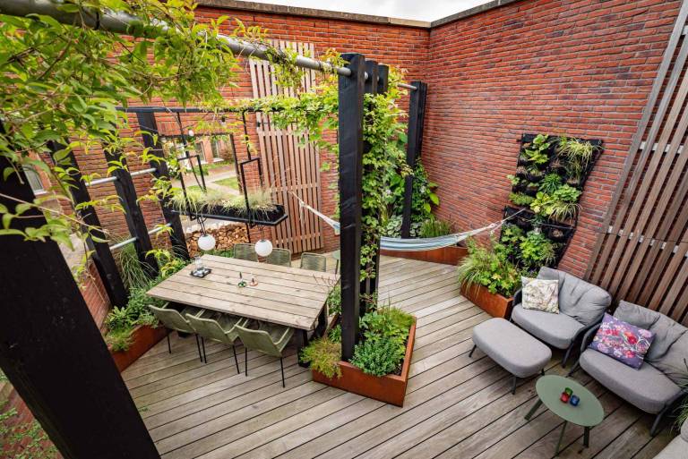 Houten terras met eettafel, lounge en plantenbakken