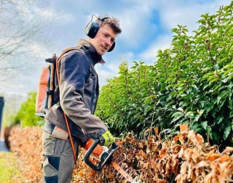 Medewerker met gehoorbescherming en tuingereedschap