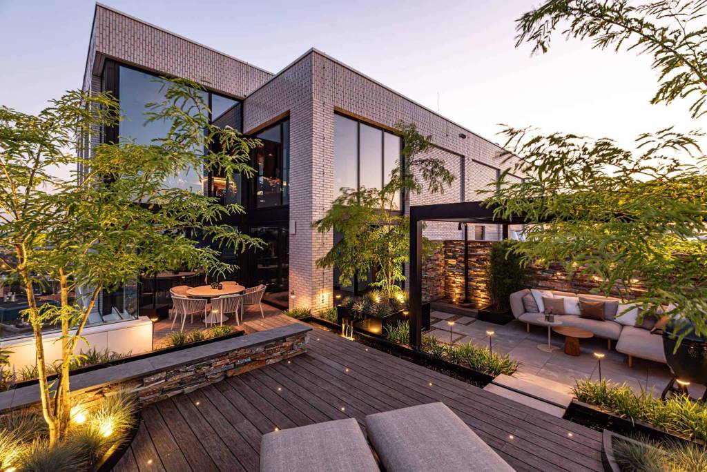 Verlichte tuin met trappen en terras bij een moderne woning