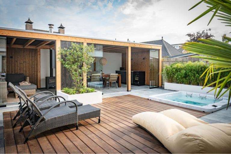 Houten terras met ligstoelen en verzonken jacuzzi