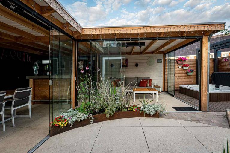 Glazen overkapping met tuintafel en groene borders