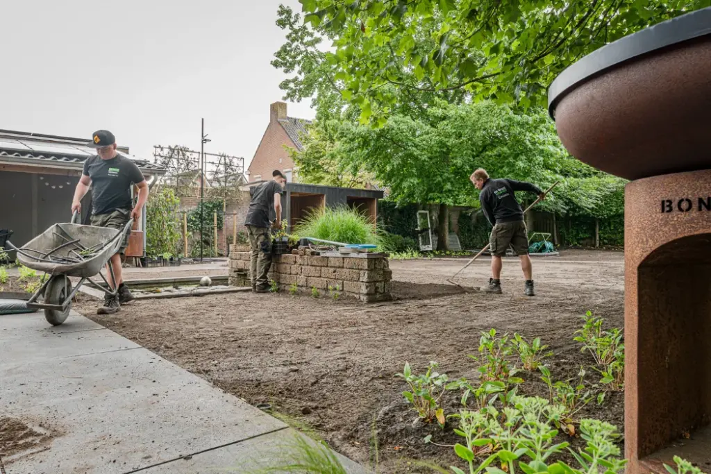 Hoveniers werken met een kruiwagen aan de aanleg van een tuin