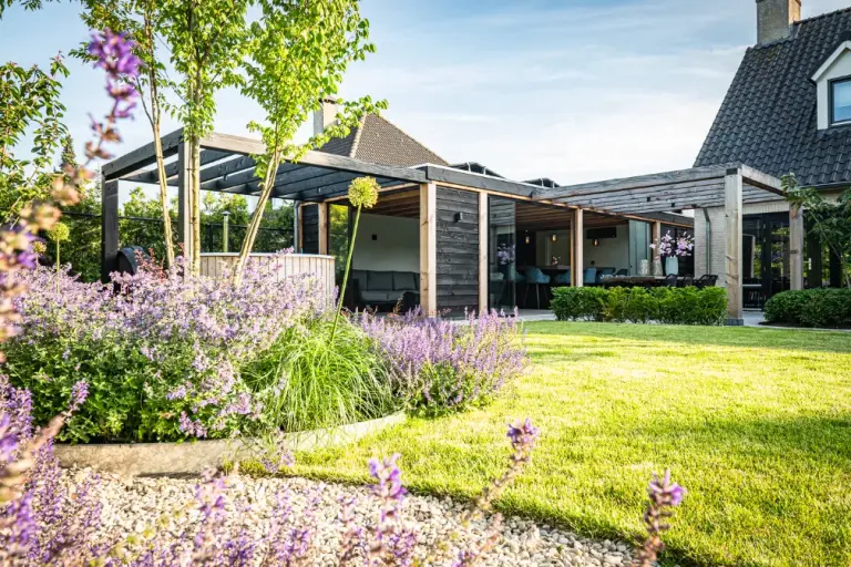 Paarse bloemen langs gazon en een tuinpaviljoen