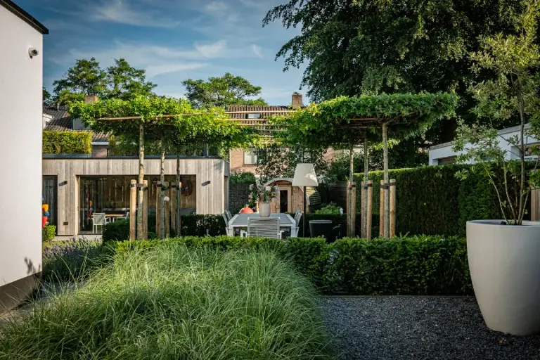 Groene tuinborders en leibomen voor een houten paviljoen