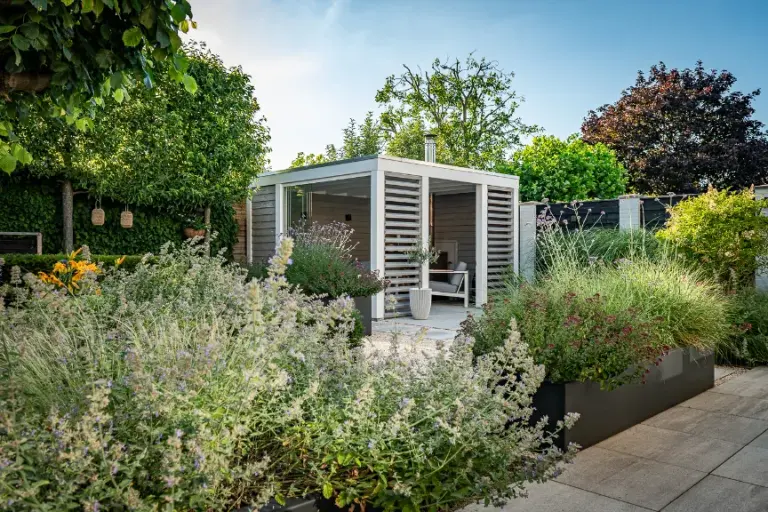 Witte overkapping tussen bloeiende tuinborders