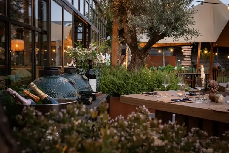 Barbecue naast bomen en lange houten tafel